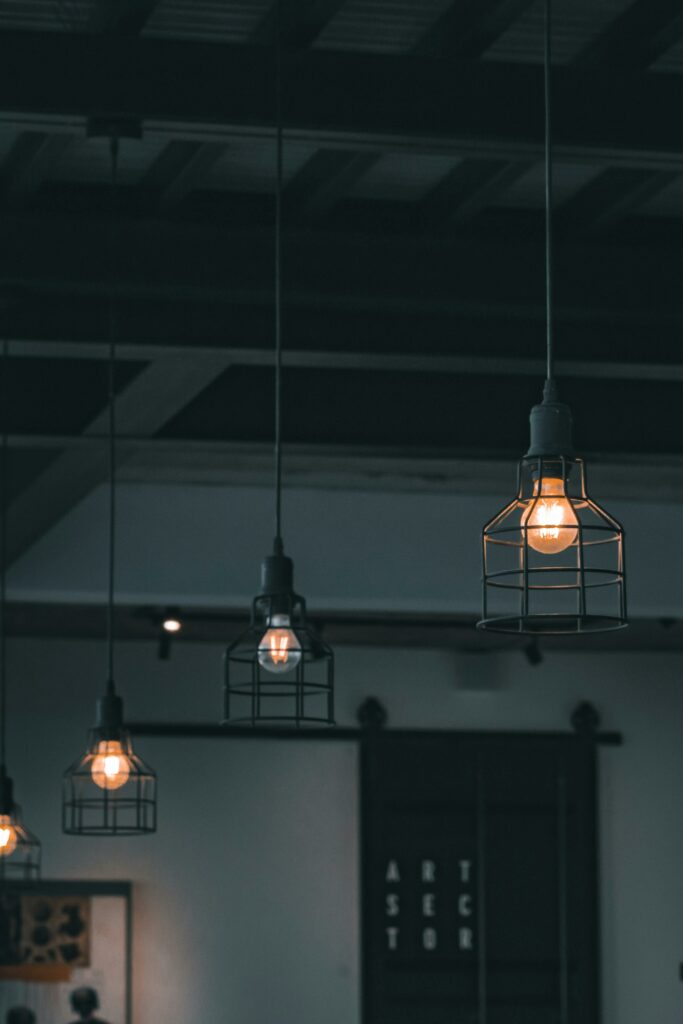 Stylish modern pendant lights with industrial design hanging in a moody urban interior setting.