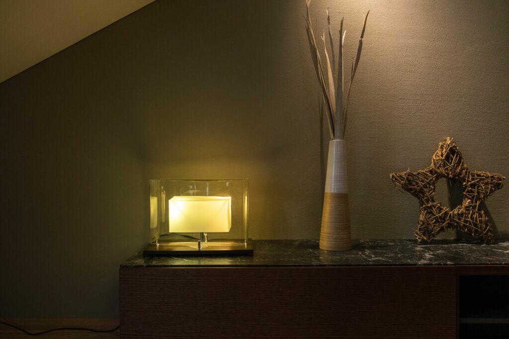 Elegant interior setup featuring a modern lamp, a tall vase with twigs, and a decorative star on a shelf.